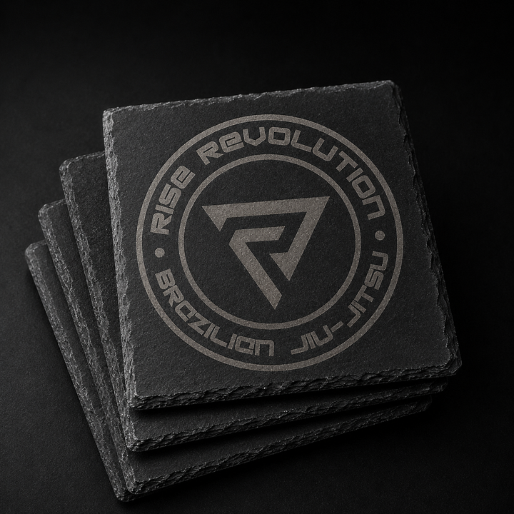 Stack of four 4 inch square natural slate coasters laser engraved with the full Rise Revolution badge